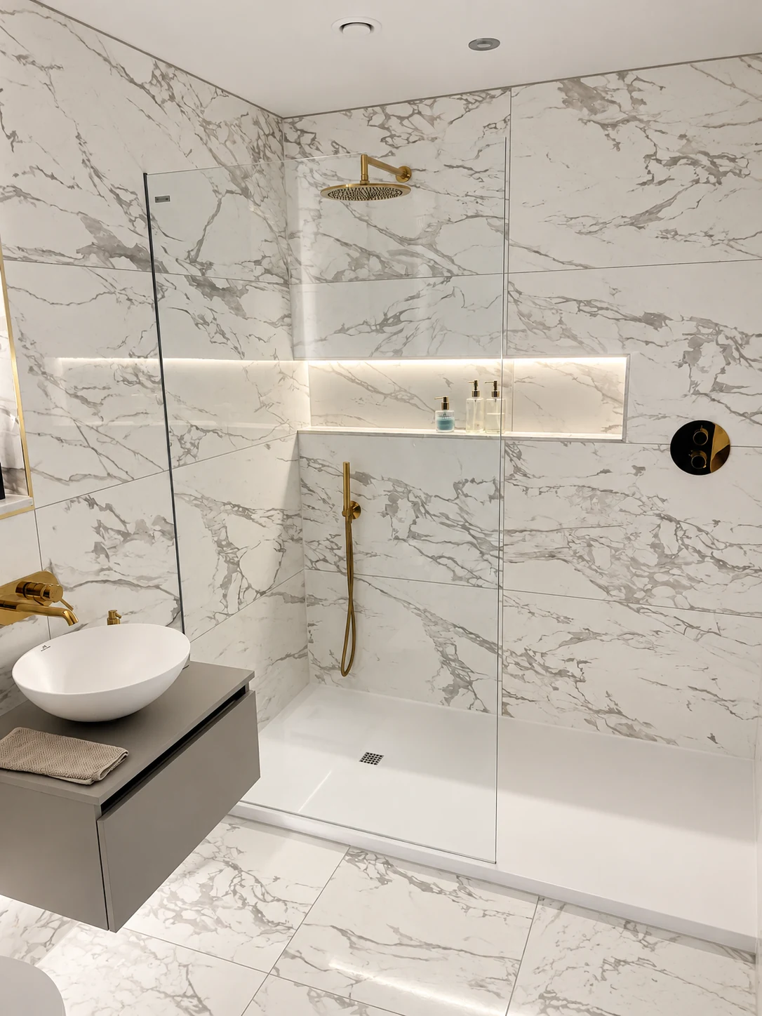 Glass walk-in shower with brass fittings, a long illuminated niche and a vessel basin