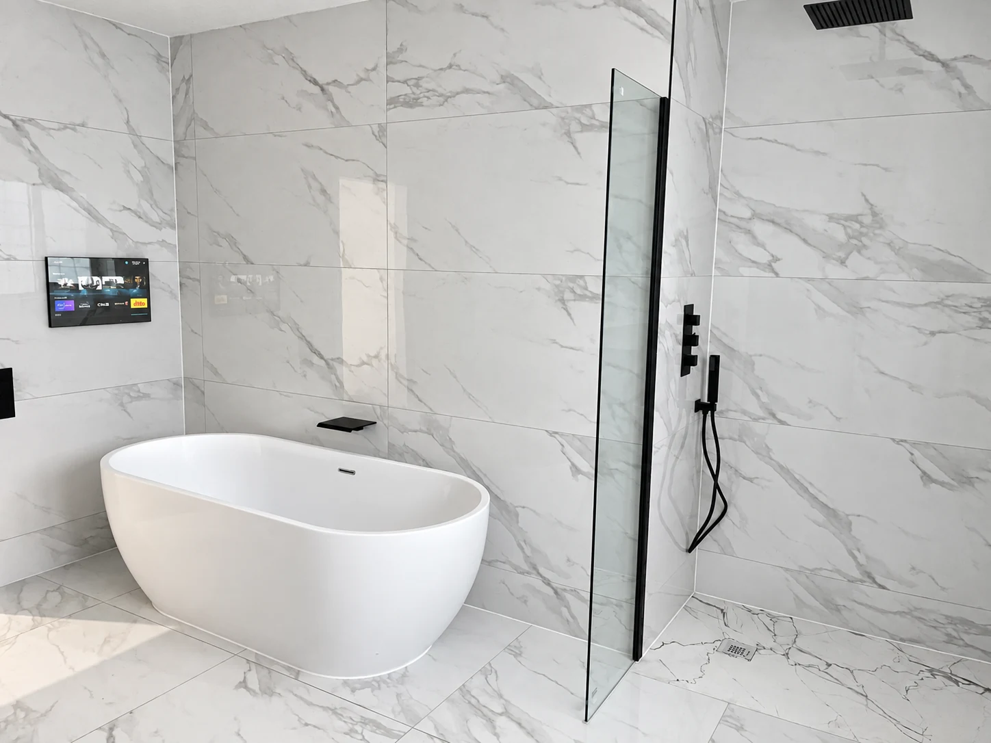 Freestanding white bath and glass walk-in shower with black fittings and marble-effect tiles